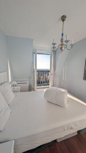 Una cama blanca grande en una habitación con ventana. en Le Panoramique, F2- vue imprenable, wifi & parking, en Blonville-sur-Mer