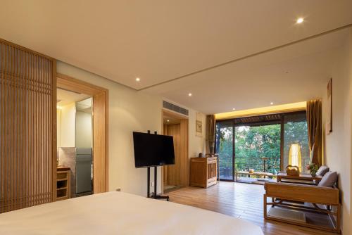 a bedroom with a bed and a television and a living room at 宏村塔川书院Hongcun Resort in Huangshan
