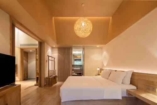 a bedroom with a white bed and a television at 宏村塔川书院Hongcun Resort in Huangshan