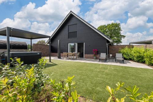 a black house with a backyard with grass at Erve Mulder vakantiehuis met eigen jacuzzi en eigen sauna in Weerselo