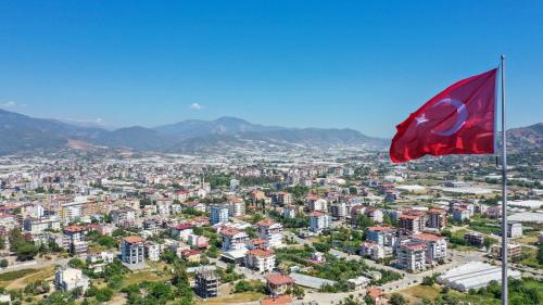 a red flag flies in front of a city at Halil Aslan Taysas Nova in Gazipasa