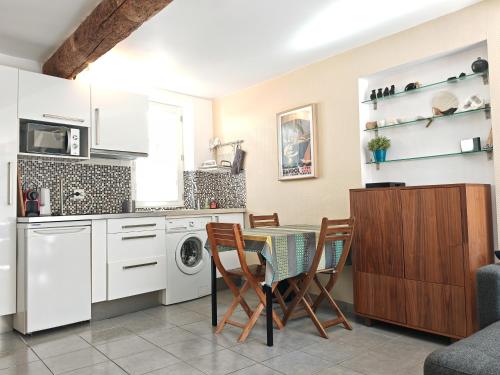 une cuisine avec des armoires blanches et une table et des chaises dans l'établissement La maison aux volets bleus, à Bandol