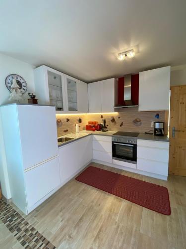 a kitchen with white cabinets and a red rug at Haus Zimba Ferienwohnung am Bartholomäberg in Bartholomäberg