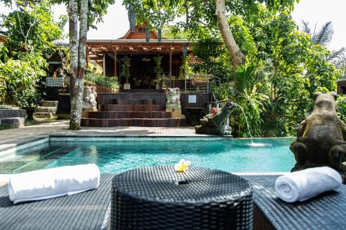 a swimming pool with a table and a house at Sacred Valley by GenuineHost in Tegalalang