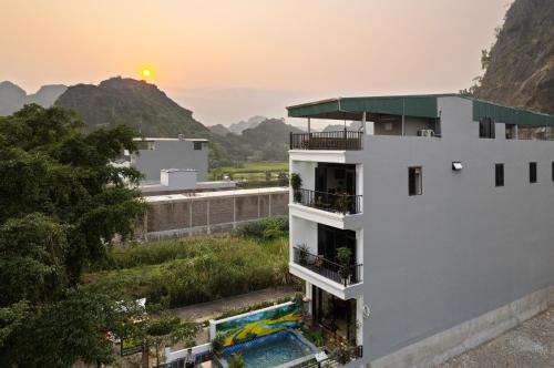 a building with a pool and the sunset in the background at Maison Tam Cốc Homestay in Vũ Lâm