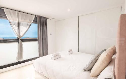 a bedroom with a white bed with a large window at Seaview house with rooftop pool, game room, parking REMS in Torremolinos