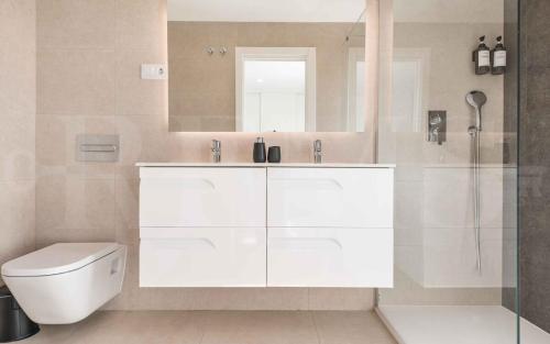 a white bathroom with a toilet and a mirror at Seaview house with rooftop pool, game room, parking REMS in Torremolinos