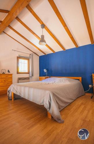 une chambre avec un grand lit avec un mur bleu dans l'établissement Sablières - Les terrasses de l’Ardèche, à Salavas