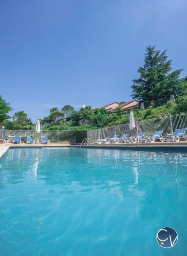 une grande piscine bleue avec chaises et parasols dans l'établissement Sablières - Les terrasses de l’Ardèche, à Salavas