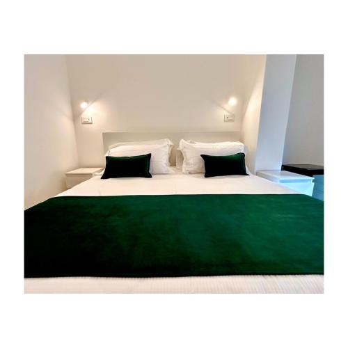 a bedroom with a large bed with green sheets and pillows at Pirandello 181 in Palermo