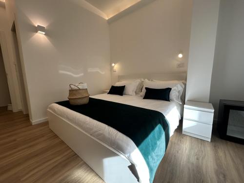 a white bedroom with a large bed with a basket on it at Pirandello 181 in Palermo