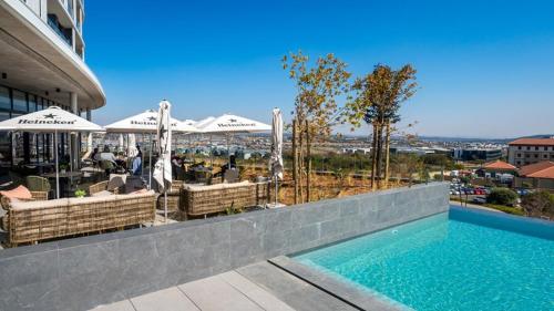 a swimming pool with tables and umbrellas on a building at Stunning 2 bedroom condo at Ellipse Midrand in Midrand
