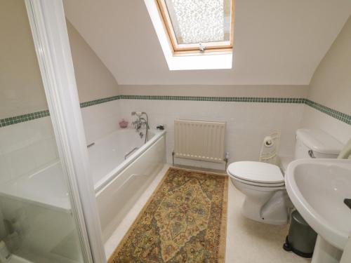 a bathroom with a toilet and a tub and a sink at Clondallon Cottage in Rathmullan