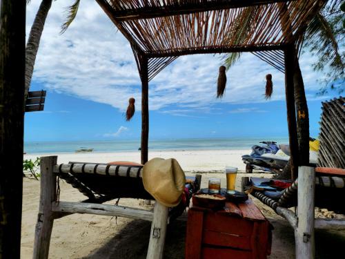 a straw hut on a beach with a view of the ocean at Ayla Beach House in Kiwengwa