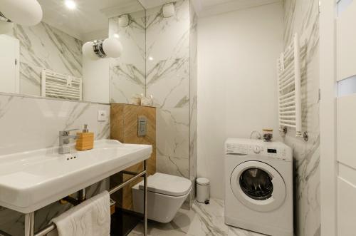 a bathroom with a sink and a washing machine at SKY Home-Sun Apartament -Manufaktura, Bezpłatny Parking, Dostęp na kod in Łódź