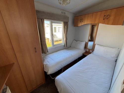 ein kleines Zimmer mit zwei Betten und einem Fenster in der Unterkunft Sherwood 307 - Golden Palm, ramped veranda, central heating, bed linen, WiFi - Meadow Lakes Caravan & Lodge Hire in Chapel Saint Leonards
