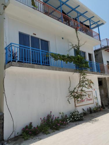 a white building with a blue balcony and flowers at Himandhoo sweet dreams in Himandhoo 