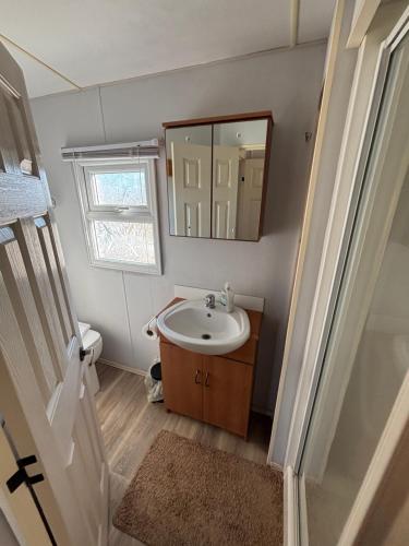 ein Badezimmer mit Waschbecken und Spiegel in der Unterkunft Sherwood 307 - Golden Palm, ramped veranda, central heating, bed linen, WiFi - Meadow Lakes Caravan & Lodge Hire in Chapel Saint Leonards