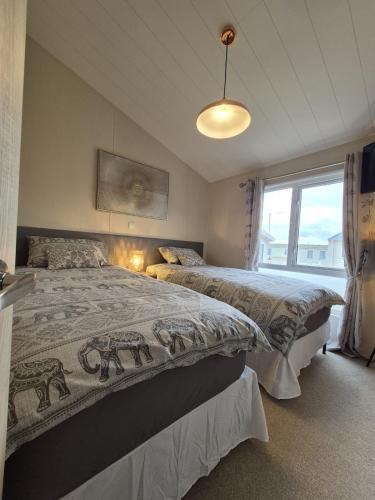 a bedroom with two beds and a large window at The Blue Lagoon 2 bedroom lodge with hot tub in Walton-on-the-Naze