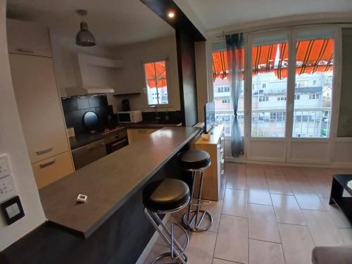 une cuisine avec un grand comptoir et deux tabourets dans l'établissement Superbe appartement 3 chambres, à Dijon