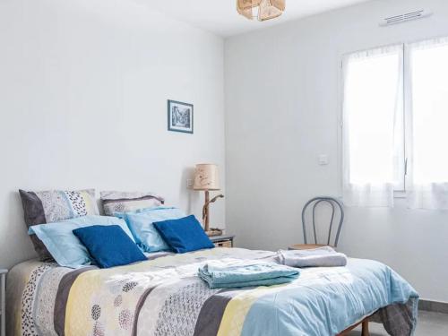 a white bedroom with a bed with blue pillows at Gite du Clos Martin in Drefféac