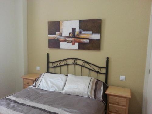 サアラ・デ・ロス・アトゥネスにあるApartamento 2H Zahara Marのベッドルーム1室(ベッド1台付)が備わります。壁には絵画が飾られています。
