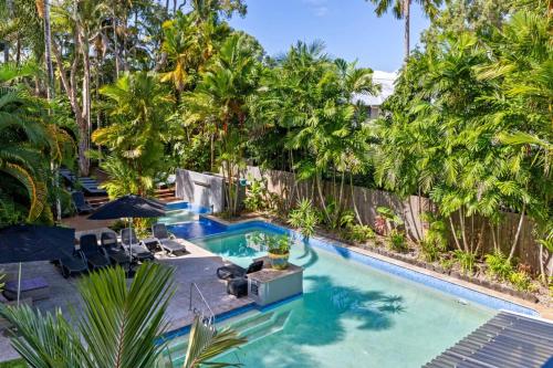 a swimming pool with chairs and palm trees at Beach-Apartments Close to Town in Port Douglas