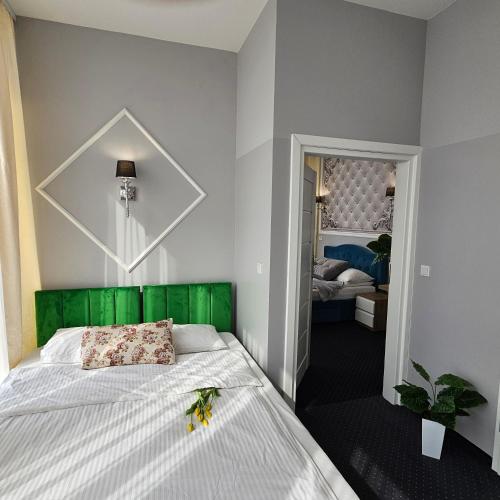 a bedroom with a bed with a green headboard at Aquila Hotel in Zator