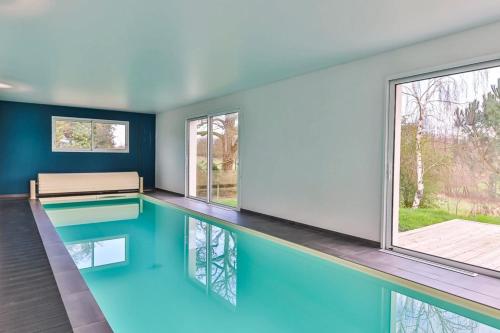 - une piscine d'eau bleue dans une chambre avec fenêtres dans l'établissement L'Atrie-Villa Piscine - Jacuzzi - Sauna, à Aizenay