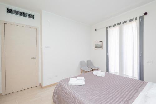 a white bedroom with a bed with two towels on it at Accogliente e moderno appartamento in zona Ospedali & Stazione in Pavia