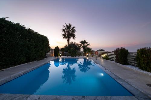 a blue swimming pool with a sunset in the background at Villa Althaea in Loutra