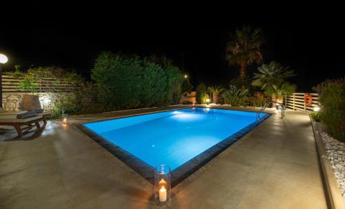 a swimming pool in a backyard at night with lights at Villa Althaea in Loutra