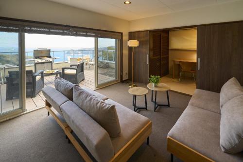 un soggiorno con divano e un balcone. di Suite Villa Atami Resort a Taga