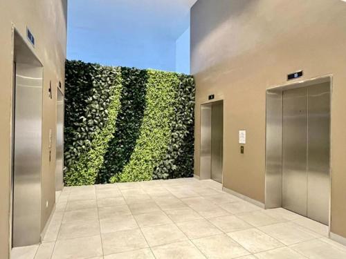 a large green wall in a hallway with elevators at The Apple Melaka in Melaka