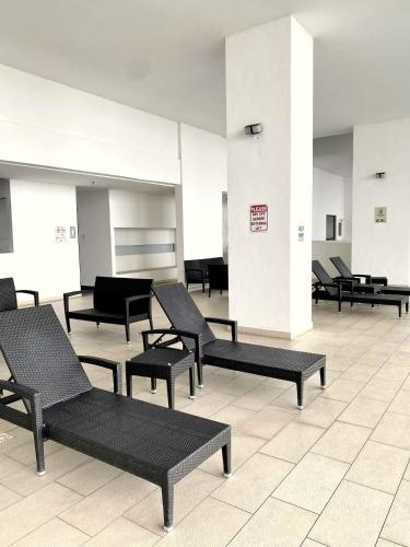 a waiting room with black chairs and tables at The Apple Melaka in Melaka