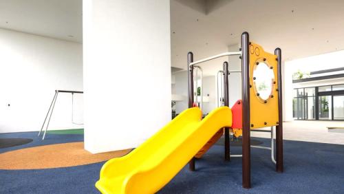 a playground with a yellow slide in a room at The Apple Melaka in Melaka