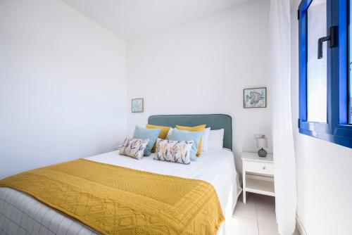 a white bedroom with a bed with a yellow blanket at Casa del Mar I in La Lajita