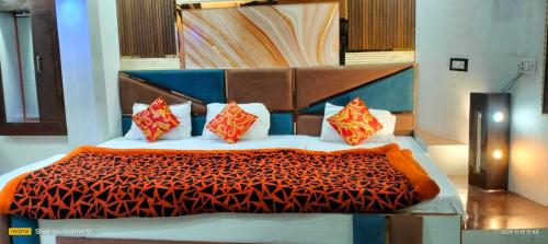 a bedroom with a bed with an orange and blue comforter at Hotel Aniruddha palace in Mathura
