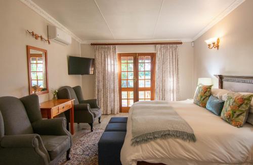 a hotel room with a bed and a desk and chairs at Bakenskraal Ostrich Palace in Oudtshoorn
