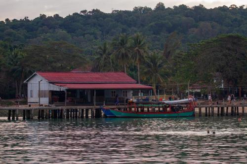 a boat is docked next to a building on the water at Koalama Cambodia in Koh Rong Sanloem