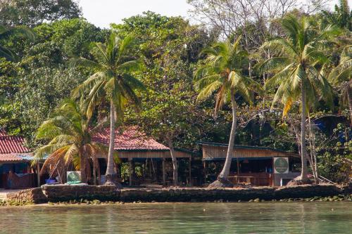 a house on the shore of the water with palm trees at Koalama Cambodia in Koh Rong Sanloem