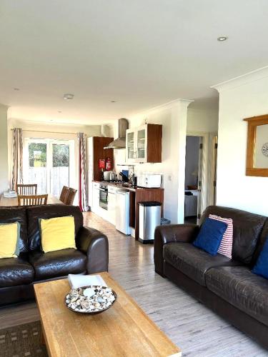 a living room with two leather couches and a table at Cape A2 Westbay Club, a 2 bedroom cottage, Isle of Wight in Yarmouth