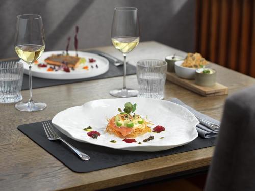 a table with a plate of food and glasses of wine at TAUROA Seehotel Grundlsee in Grundlsee