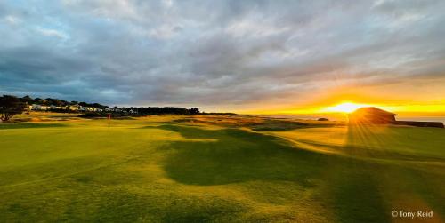 a golf course with the sunset in the background at The Clubhouse Nairn in Nairn