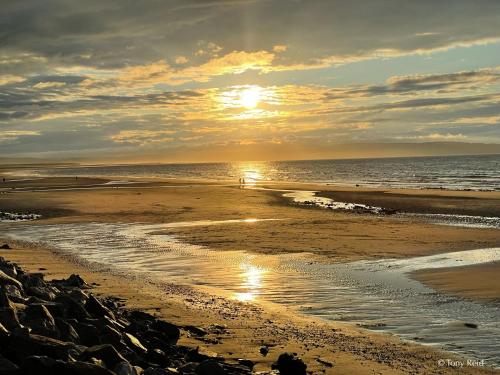 a person walking on the beach at sunset at The Clubhouse Nairn in Nairn