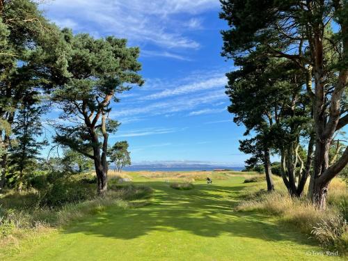 a golf course with trees on a green at The Clubhouse Nairn in Nairn