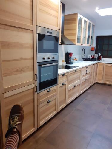 - une cuisine avec des placards en bois et un pied de personne au sol dans l'établissement Villa Maky Enea, à Biarritz