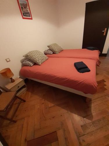 Cette chambre comprend un lit avec des draps rouges et du parquet. dans l'établissement Villa Maky Enea, à Biarritz