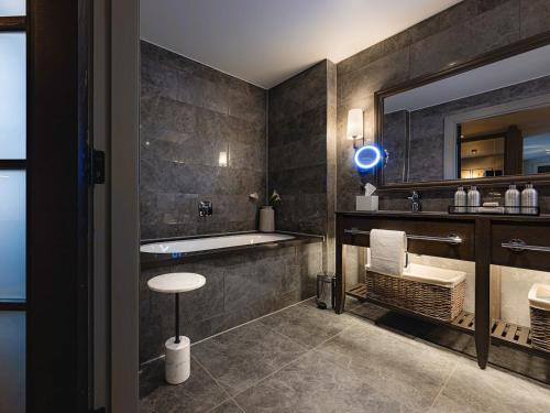 a bathroom with a tub and a sink and a mirror at Dakota Newcastle in Newcastle upon Tyne