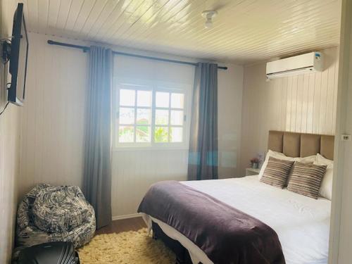 a bedroom with a large bed and a window at Chalé Vale do Floresta in Gramado
